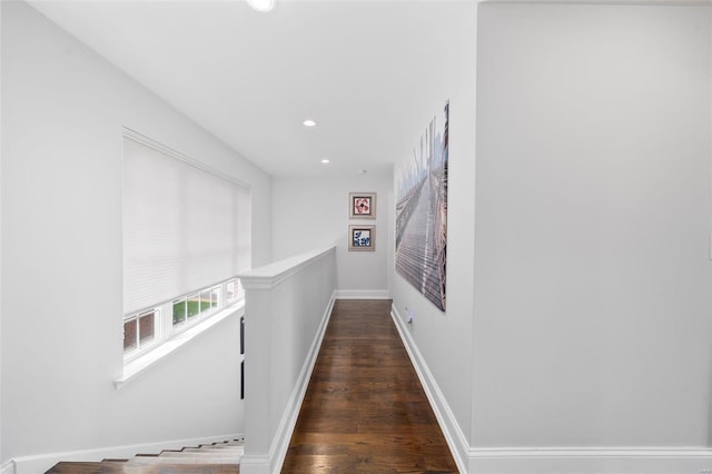 hallway featuring recessed lighting, baseboards, wood finished floors, and an upstairs landing