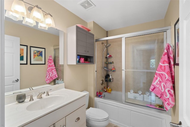 full bath featuring vanity, combined bath / shower with glass door, toilet, and visible vents