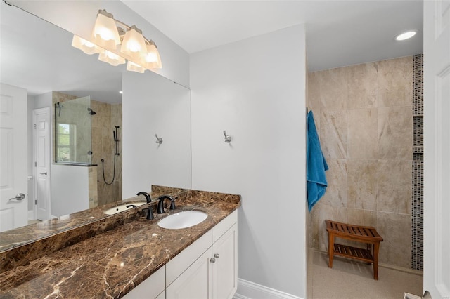 bathroom with baseboards, tiled shower, and vanity