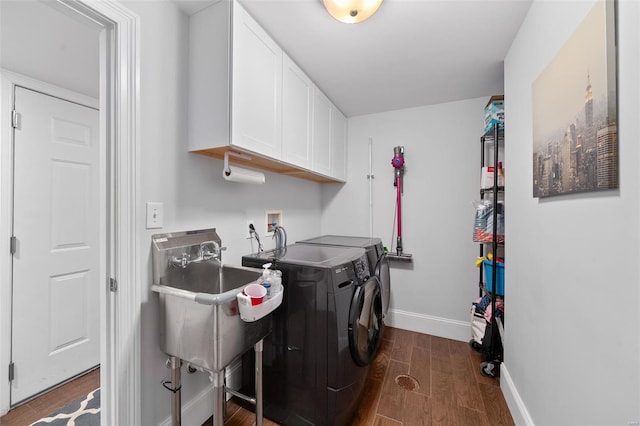 laundry area featuring cabinet space, independent washer and dryer, a sink, baseboards, and dark wood-style floors