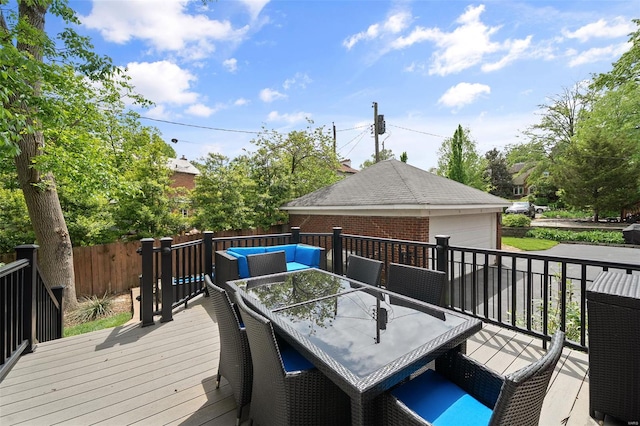 deck featuring a garage, fence, and outdoor dining space