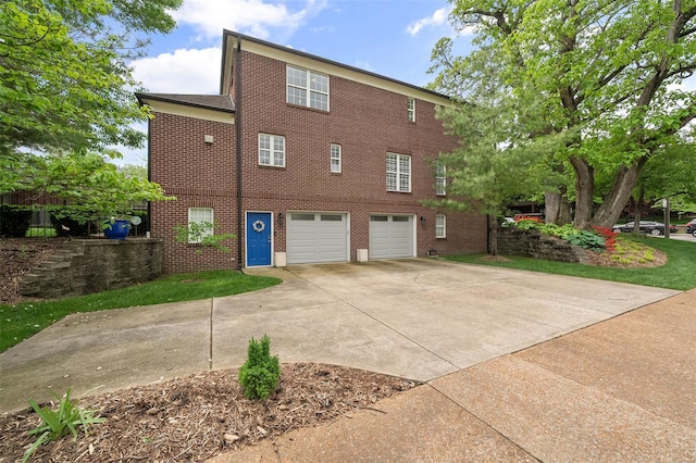 back of house featuring brick siding, driveway, and a garage
