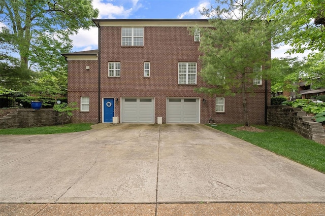 rear view of property featuring an attached garage, concrete driveway, and brick siding