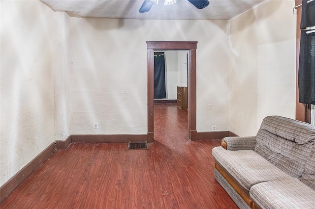 living area with wood finished floors, visible vents, a ceiling fan, and baseboards