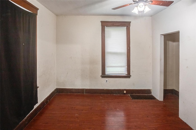 empty room featuring dark wood finished floors, visible vents, a ceiling fan, and baseboards