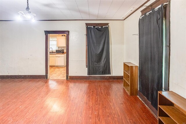 spare room with baseboards, wood finished floors, and a sink
