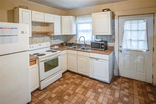 kitchen featuring backsplash, brick patterned floor, a sink, and white appliances