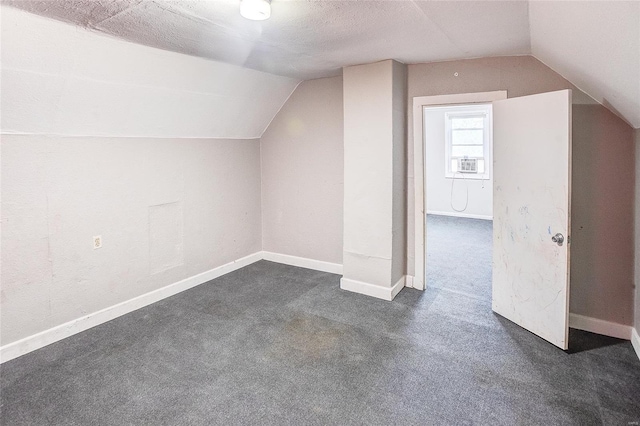 additional living space featuring cooling unit, vaulted ceiling, baseboards, and dark colored carpet