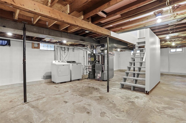below grade area featuring heating unit, water heater, stairs, and washing machine and clothes dryer