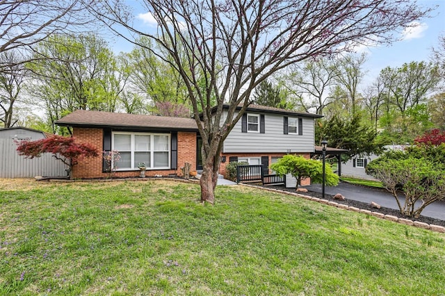split level home with aphalt driveway, a front lawn, and brick siding