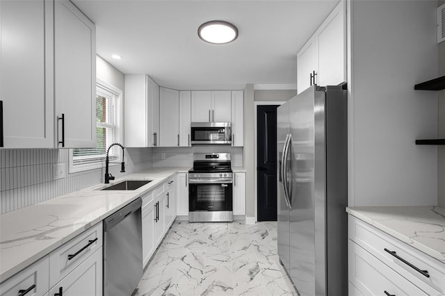 kitchen featuring marble finish floor, backsplash, a sink, appliances with stainless steel finishes, and white cabinetry
