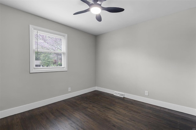 empty room with dark wood finished floors, baseboards, a ceiling fan, and visible vents