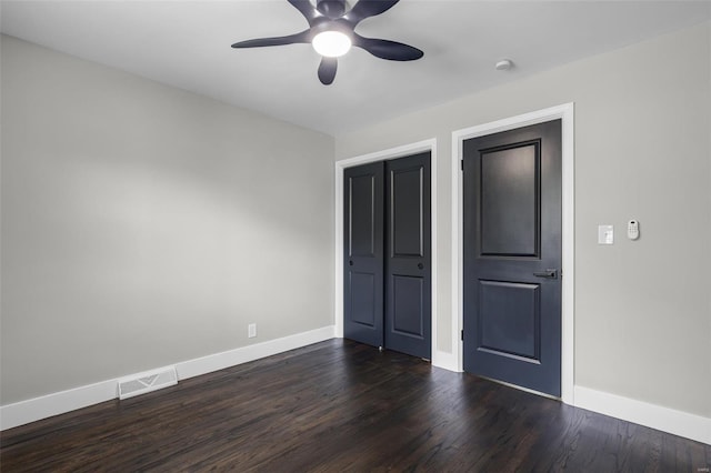unfurnished bedroom with baseboards, a ceiling fan, visible vents, and dark wood finished floors