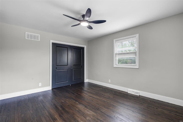 unfurnished bedroom featuring baseboards, dark wood-style flooring, and visible vents
