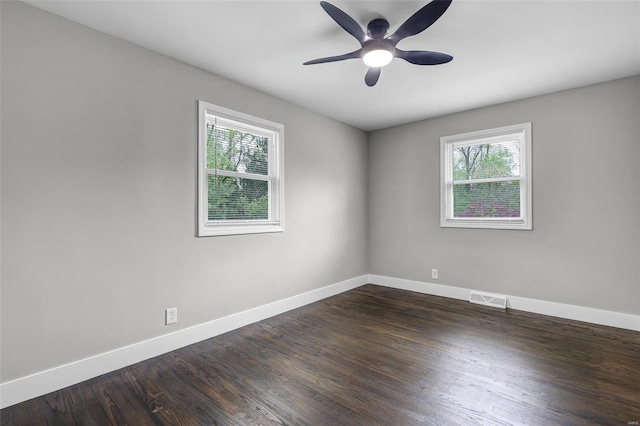 empty room with visible vents, plenty of natural light, baseboards, and dark wood-type flooring