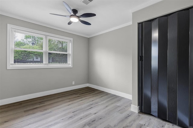 unfurnished bedroom with ceiling fan, baseboards, crown molding, and light wood-style floors