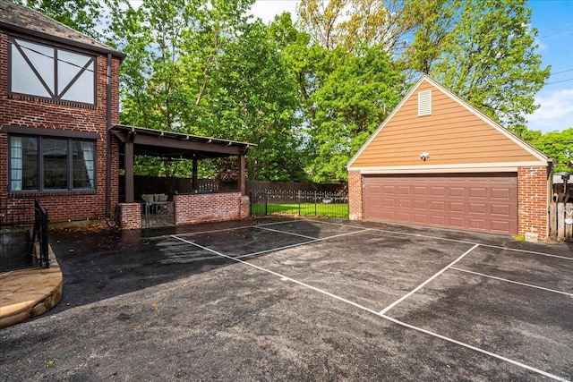 exterior space with fence, an outdoor structure, a garage, and brick siding