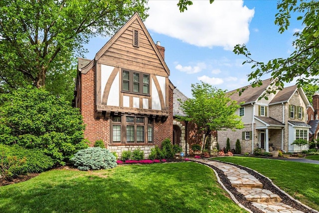 tudor home with a chimney, stone siding, and a front lawn