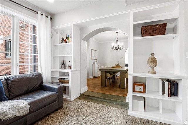 sitting room featuring crown molding, arched walkways, and a chandelier