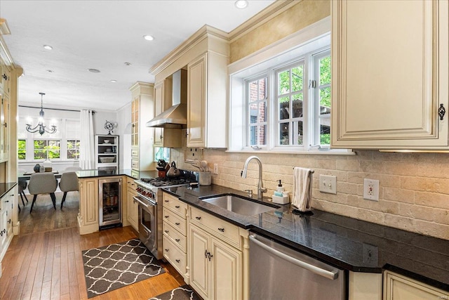 kitchen with a sink, appliances with stainless steel finishes, cream cabinetry, and wine cooler