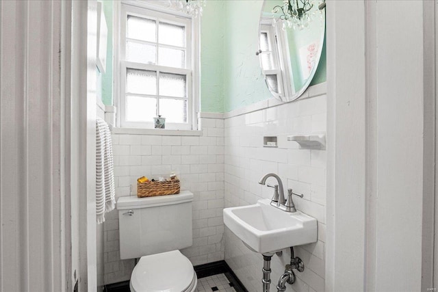 bathroom with a sink, tile walls, wainscoting, and toilet