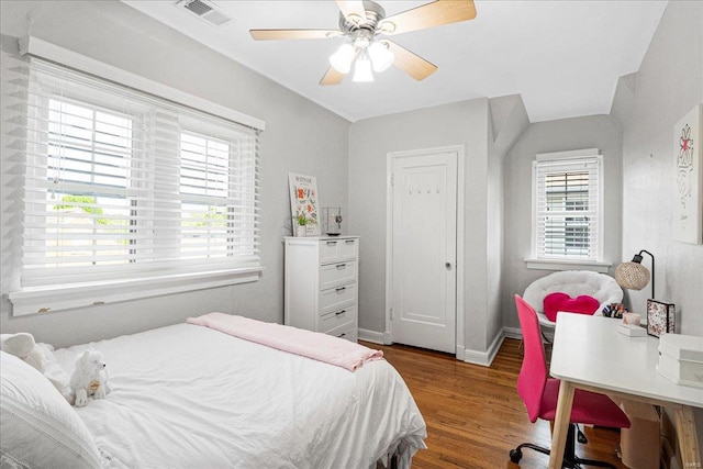 bedroom with visible vents, baseboards, wood finished floors, and multiple windows