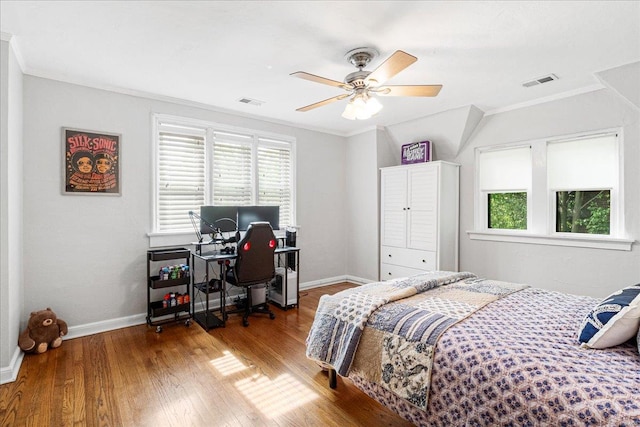 bedroom featuring ornamental molding, wood finished floors, and multiple windows
