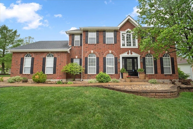 colonial-style house featuring brick siding and a front lawn