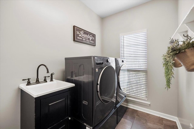 laundry area with a sink, washing machine and clothes dryer, cabinet space, and baseboards