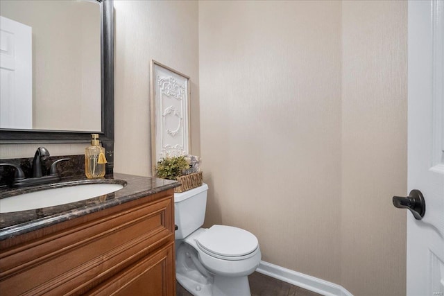 bathroom featuring vanity, toilet, and baseboards