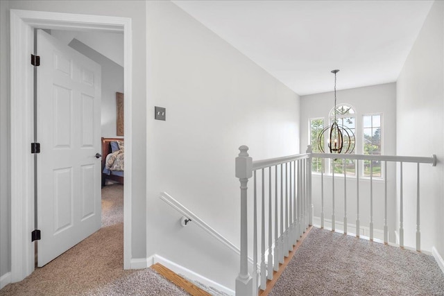 staircase with a chandelier, baseboards, and carpet floors