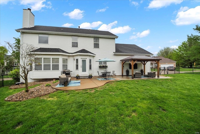 back of house with a gazebo, a patio area, a chimney, a lawn, and a fenced backyard