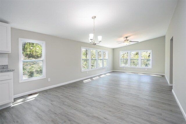 unfurnished dining area with visible vents, light wood-style floors, ceiling fan with notable chandelier, and baseboards