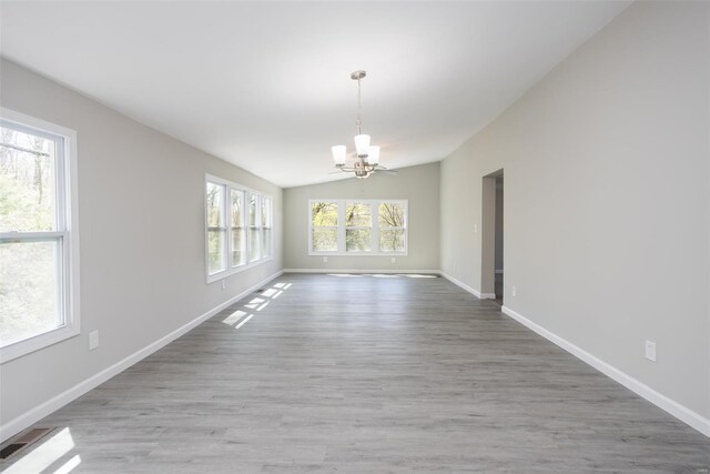 unfurnished dining area with baseboards, a chandelier, wood finished floors, and vaulted ceiling