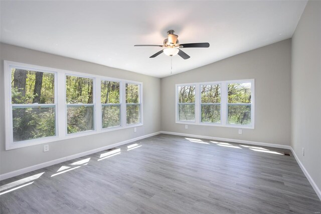 spare room featuring visible vents, wood finished floors, lofted ceiling, baseboards, and ceiling fan