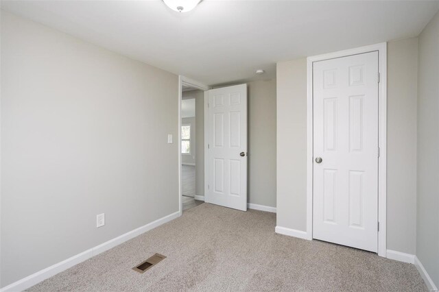 unfurnished bedroom with baseboards, visible vents, and carpet