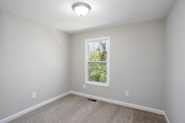 carpeted spare room featuring baseboards and visible vents
