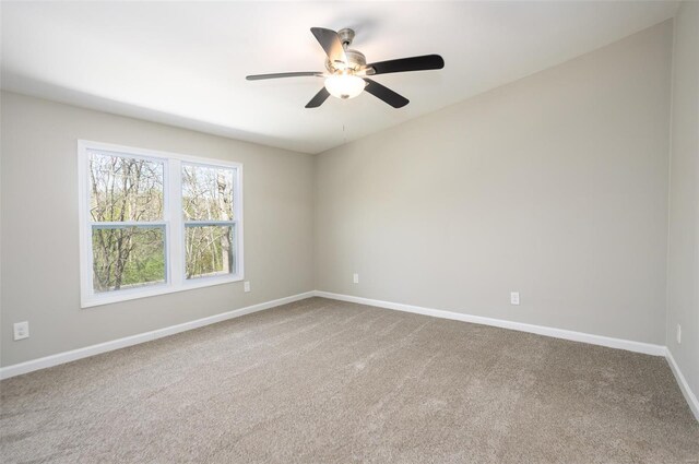 spare room with carpet floors, a ceiling fan, and baseboards