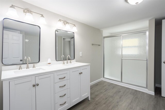 full bath featuring double vanity, a sink, wood finished floors, and a shower stall