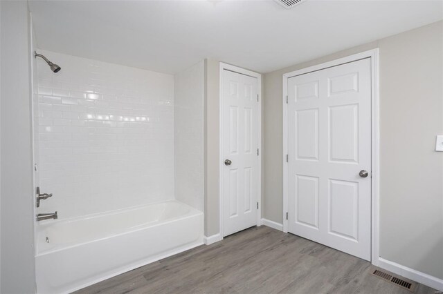 full bathroom with visible vents, tub / shower combination, baseboards, and wood finished floors