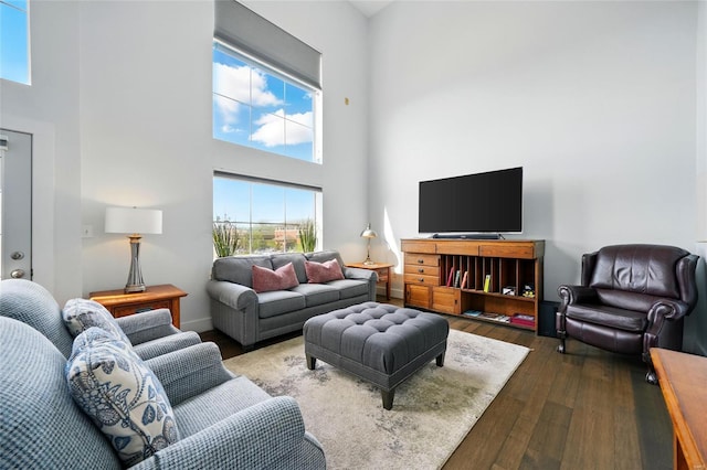 living room with dark wood-type flooring and a towering ceiling