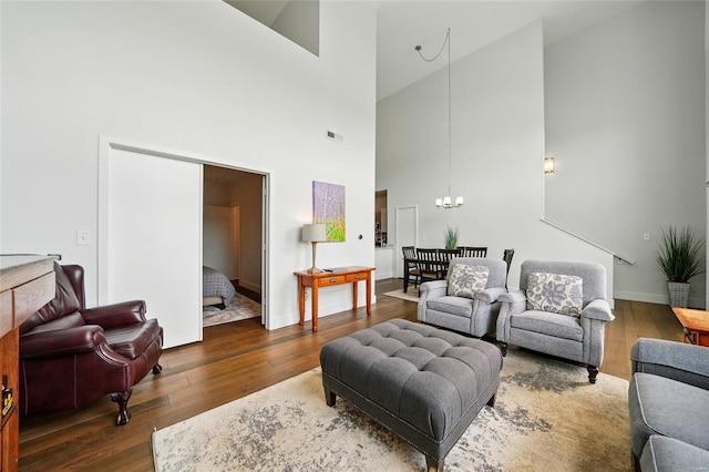 living room featuring a chandelier, hardwood / wood-style flooring, high vaulted ceiling, and baseboards