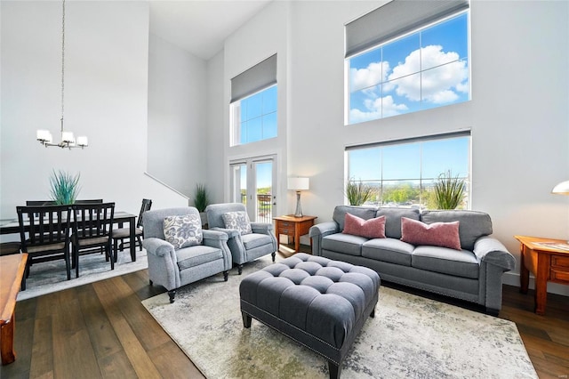 living area featuring an inviting chandelier, dark wood-style floors, and a high ceiling