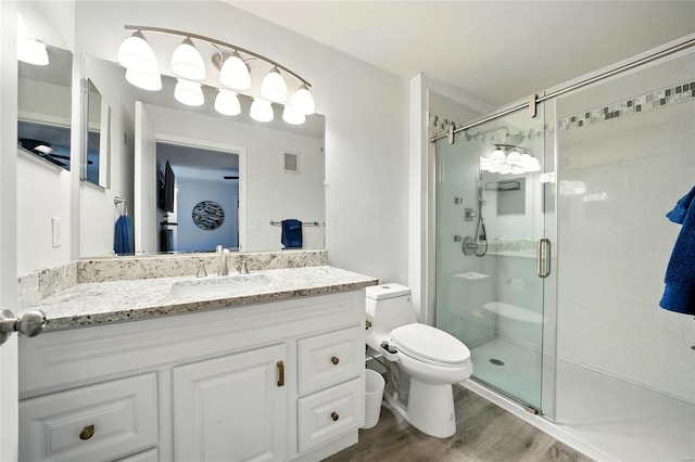 bathroom featuring toilet, visible vents, a shower stall, and wood finished floors