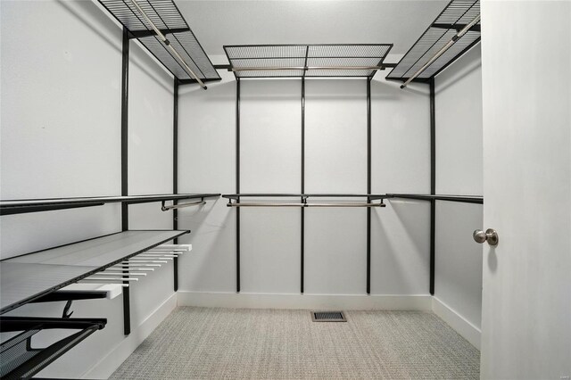 walk in closet featuring visible vents and light carpet