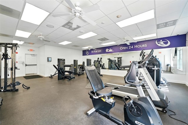 exercise room with baseboards, ceiling fan, and a paneled ceiling