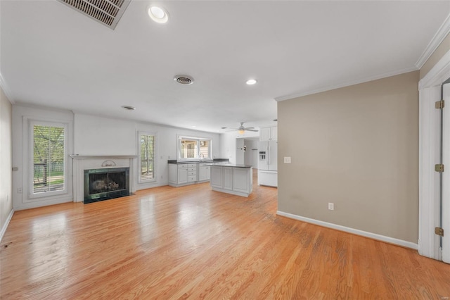 unfurnished living room with recessed lighting, ornamental molding, baseboards, visible vents, and a fireplace with flush hearth
