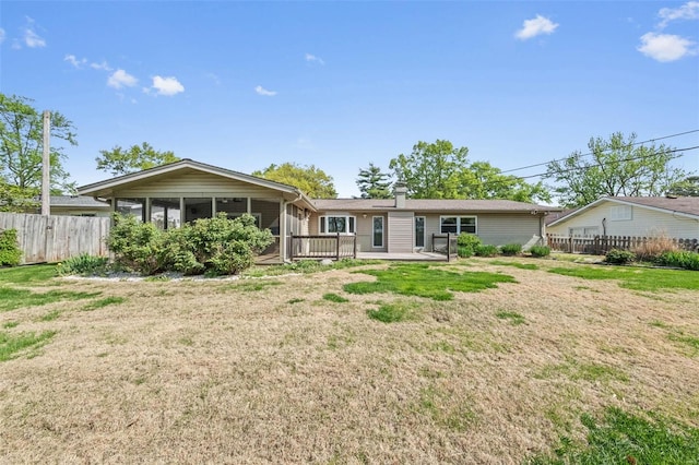 rear view of house with fence, a yard, and a sunroom