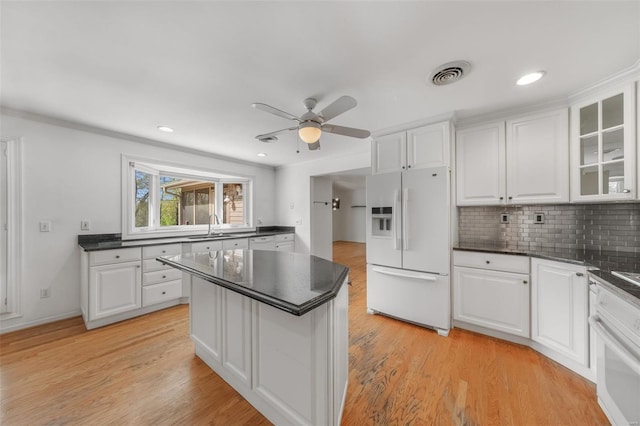 kitchen featuring visible vents, a sink, white cabinets, and white appliances