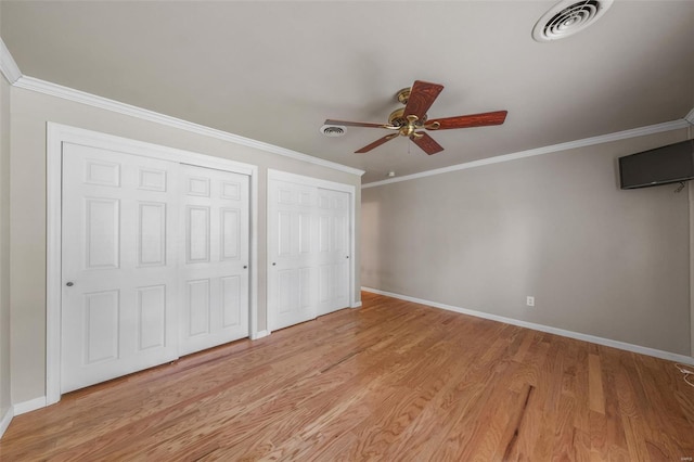 unfurnished bedroom with visible vents, multiple closets, crown molding, and baseboards